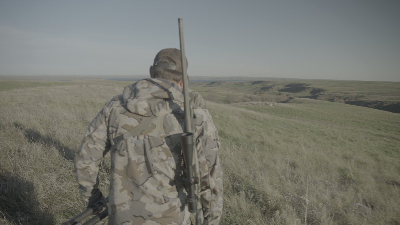 A hunter walking across grassland